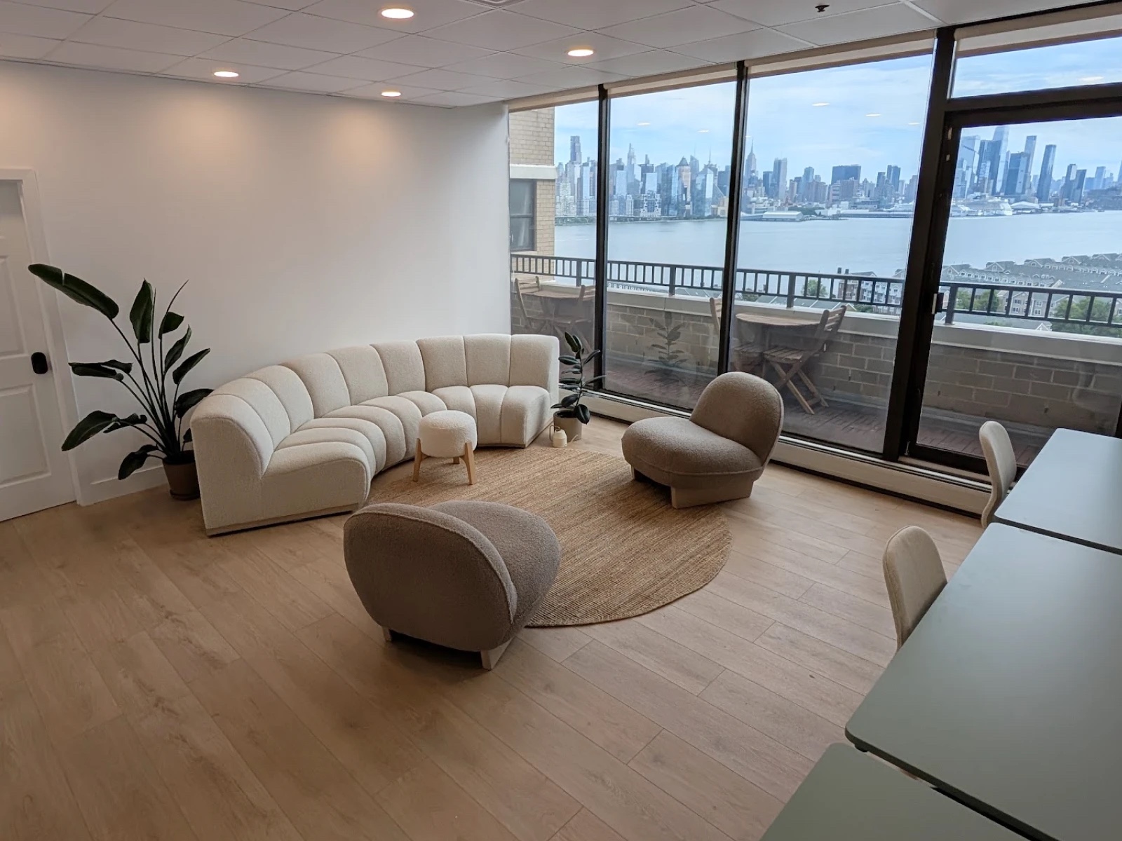 The creative studio at HudsonDesk — bouclé couch and armchairs facing the terrace and the Manhattan skyline
